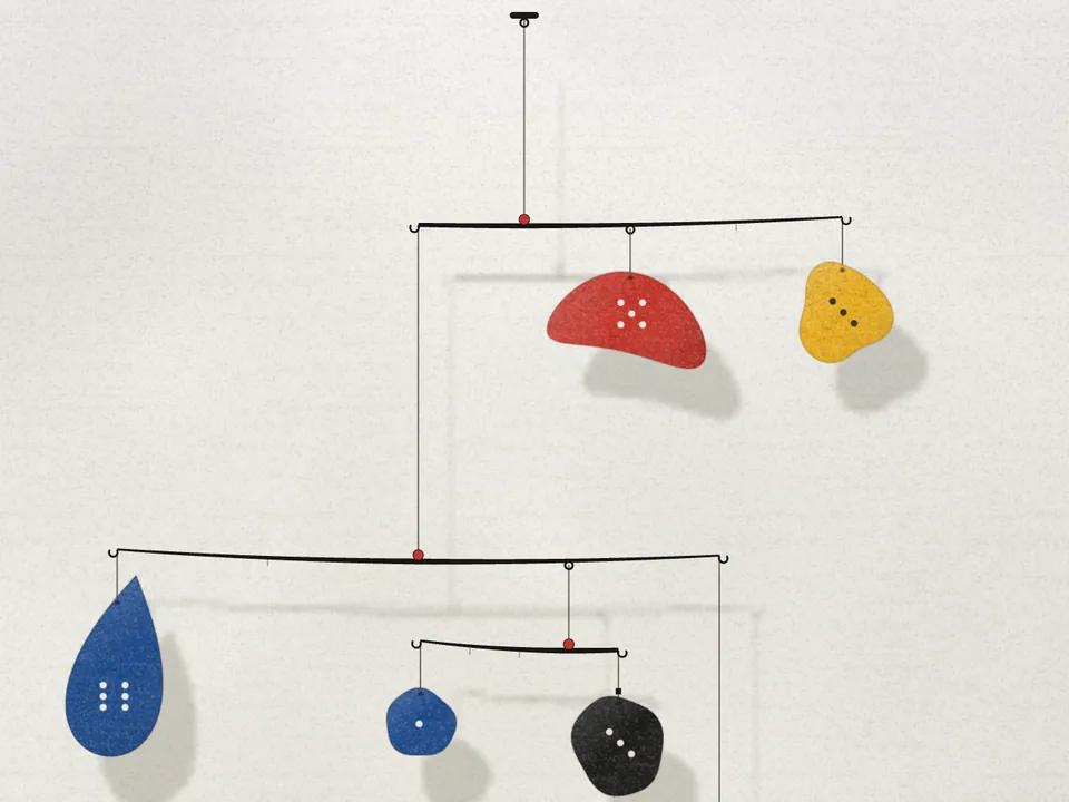 A hanging mobile of red, yellow, blue and black shapes on a plaster wall